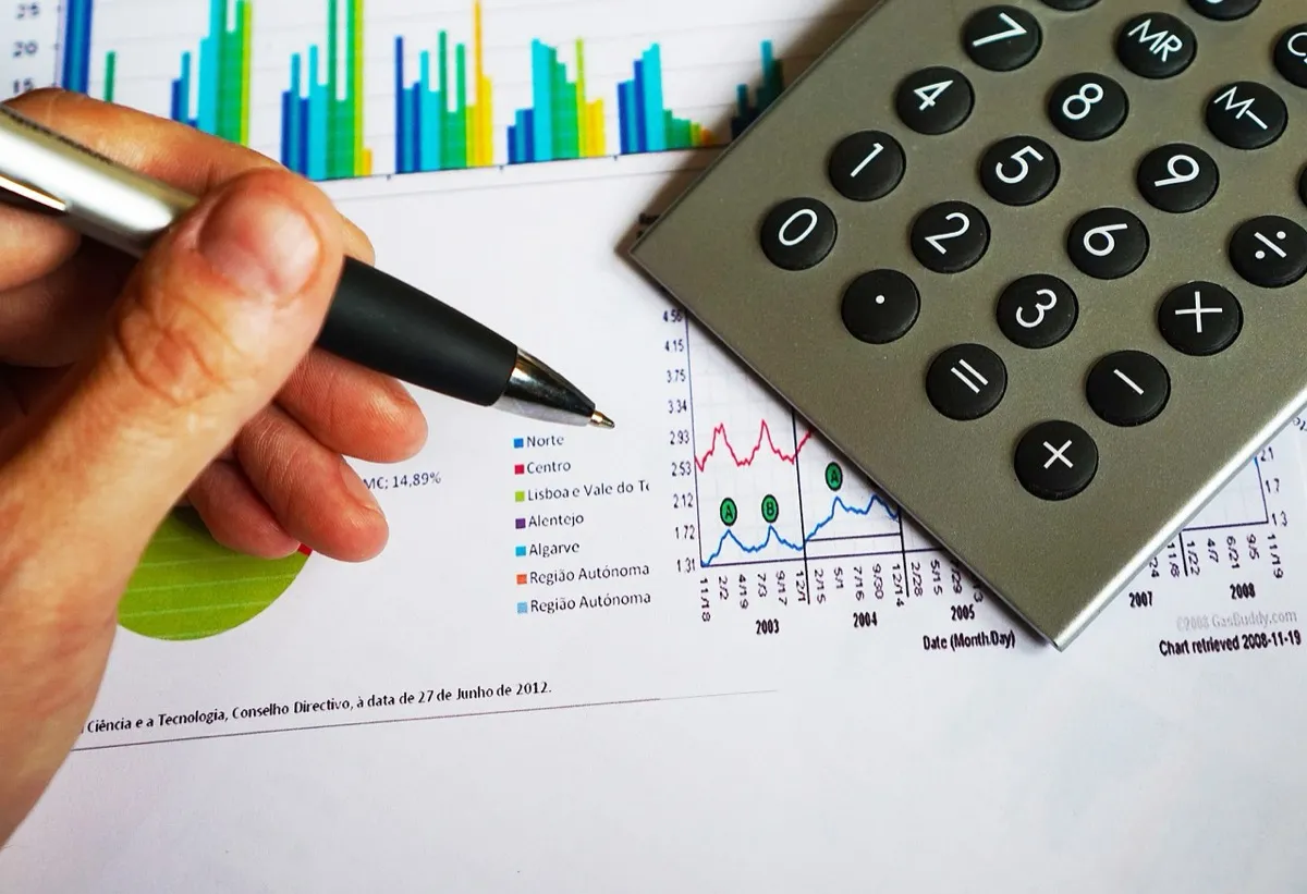 A pen and a calculator lying on printed financial charts during a year-end tax calculation